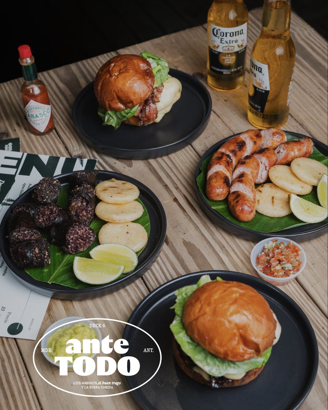 Mesa con hamburguesas, morcilla con arepas, chorizo y cervezas de Ante Todo
